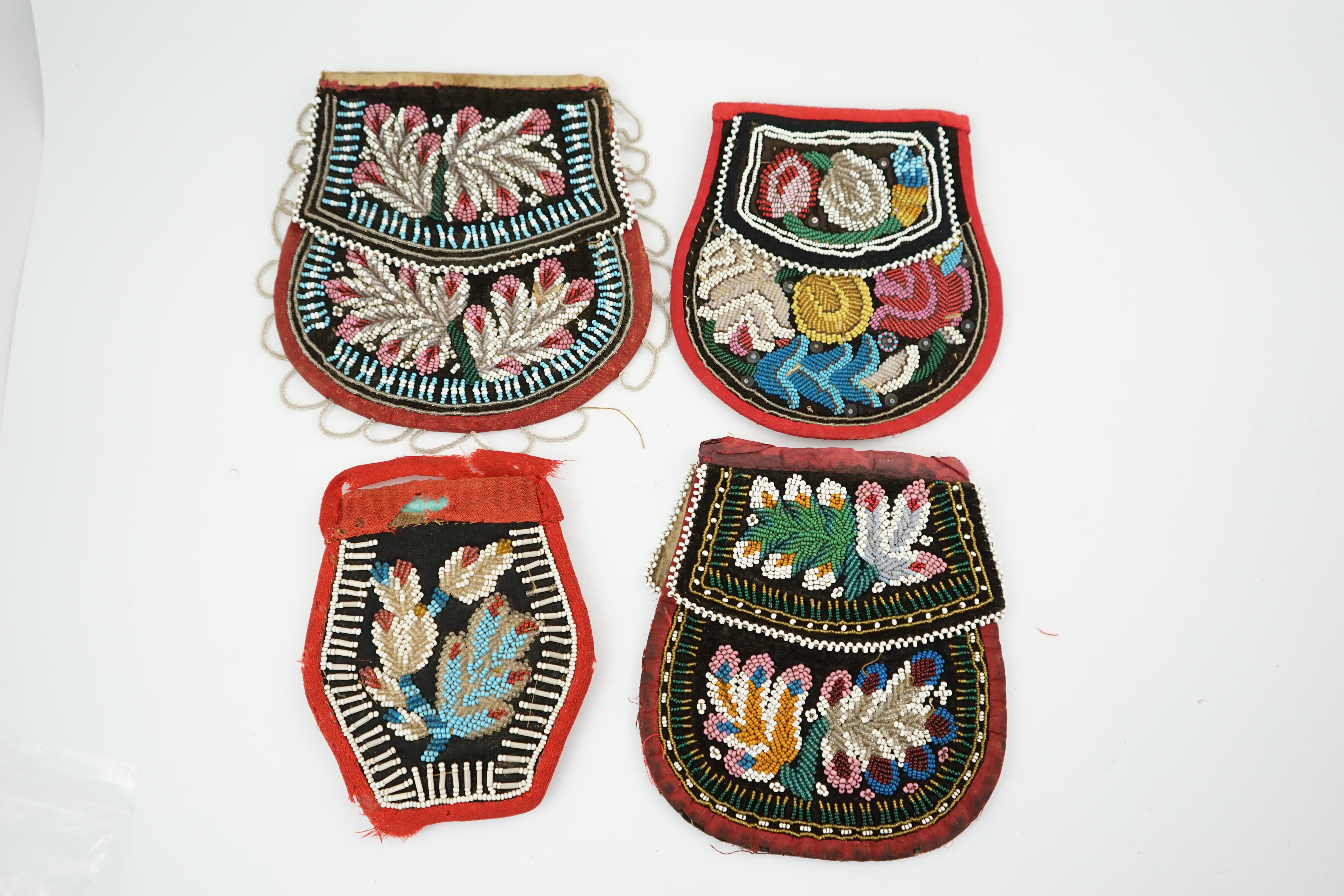 Three 19th century Iroquois Native American beaded bags and a smaller pouch, the bags have beaded flaps, the pouch is shaped with mostly white and turquoise beading having a red fabric edging, all four have very differen